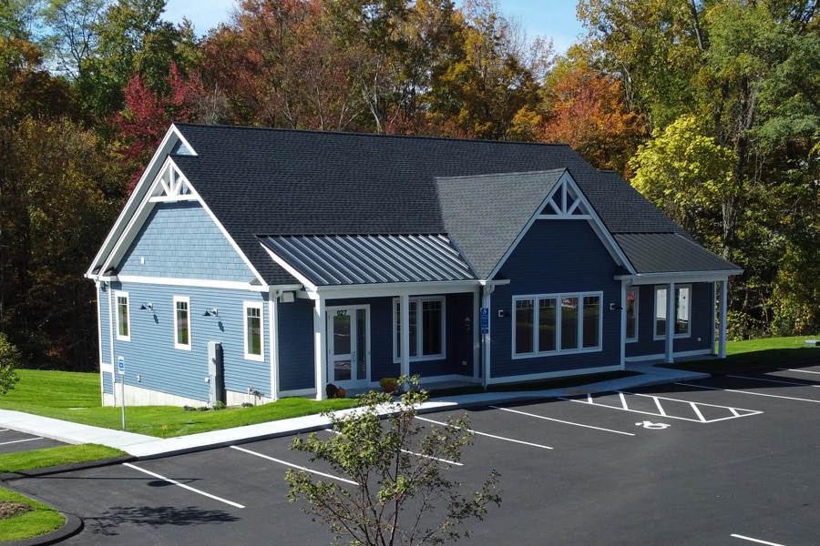 Exterior view of the Griffin Orthodontics office building with parking area and surrounding trees, helping patients identify the practice location at Griffin Orthodontics, Vernon, CT 06066.
