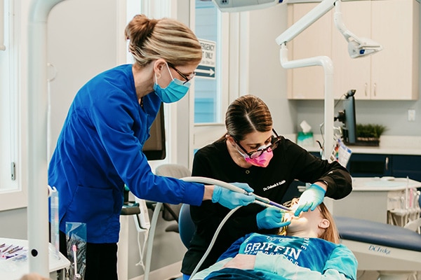 Orthodontic team members providing chairside care to a patient in a treatment room, representing evaluation and treatment of common orthodontic issues at Griffin Orthodontics, Vernon, CT 06066.