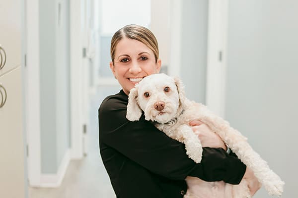 Dr. Deborah Griffin smiling while holding a small white dog in a bright orthodontic office, introducing her personalized approach to modern orthodontic care at Griffin Orthodontics, Vernon, CT 06066.