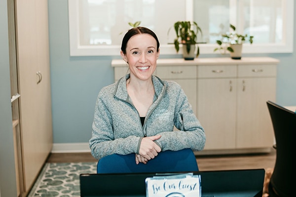 Griffin Orthodontics team member smiling at the front desk in a welcoming office area, representing appointment requests and patient support at Griffin Orthodontics, Vernon, CT 06066.