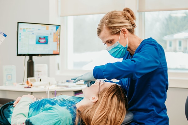 Orthodontic team member providing chairside care to a patient in a bright treatment room, representing Spark Clear Aligner treatment at Griffin Orthodontics, Vernon, CT 06066.